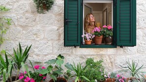 A stone building with a window featuring green shutters. - Turrium Heritage Apartment con Patio e Camino Fronte Mare (Kaštel Kambelovac)