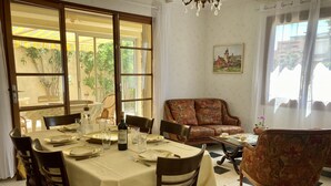 Zona pranzo con tavolo imbandito per quattro persone, un divano e un quadro appeso al muro.