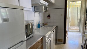 Cucina con elettrodomestici bianchi, mobili in legno e vista all'esterno.