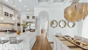 A spacious kitchen with white cabinetry, a central island, and a dining area with a long table.
