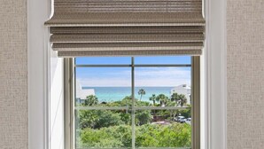 A window with a view of the ocean and greenery.