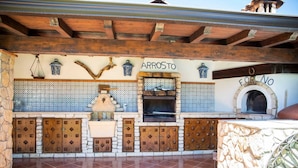 A rustic outdoor kitchen with a stone wall, wooden cabinets, and a tiled backsplash. - [✮✮✮✮✮ LUXURY VILLA WITH POOL] - Dimora Fanale (Torre Colonna-Sperone)