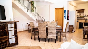A dining area with wicker chairs and a wooden table, a staircase, a white sofa, and a kitchen in the background. - [✮✮✮✮✮ LUXURY VILLA WITH POOL] - Dimora Fanale (Torre Colonna-Sperone)