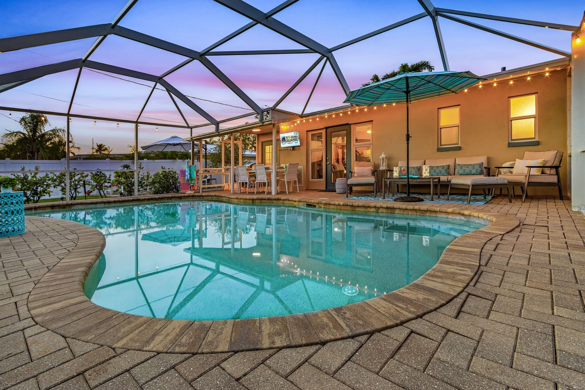 Ein Poolbereich mit überdachter Terrasse, Sitzmöglichkeiten im Freien und Blick aufs Meer.