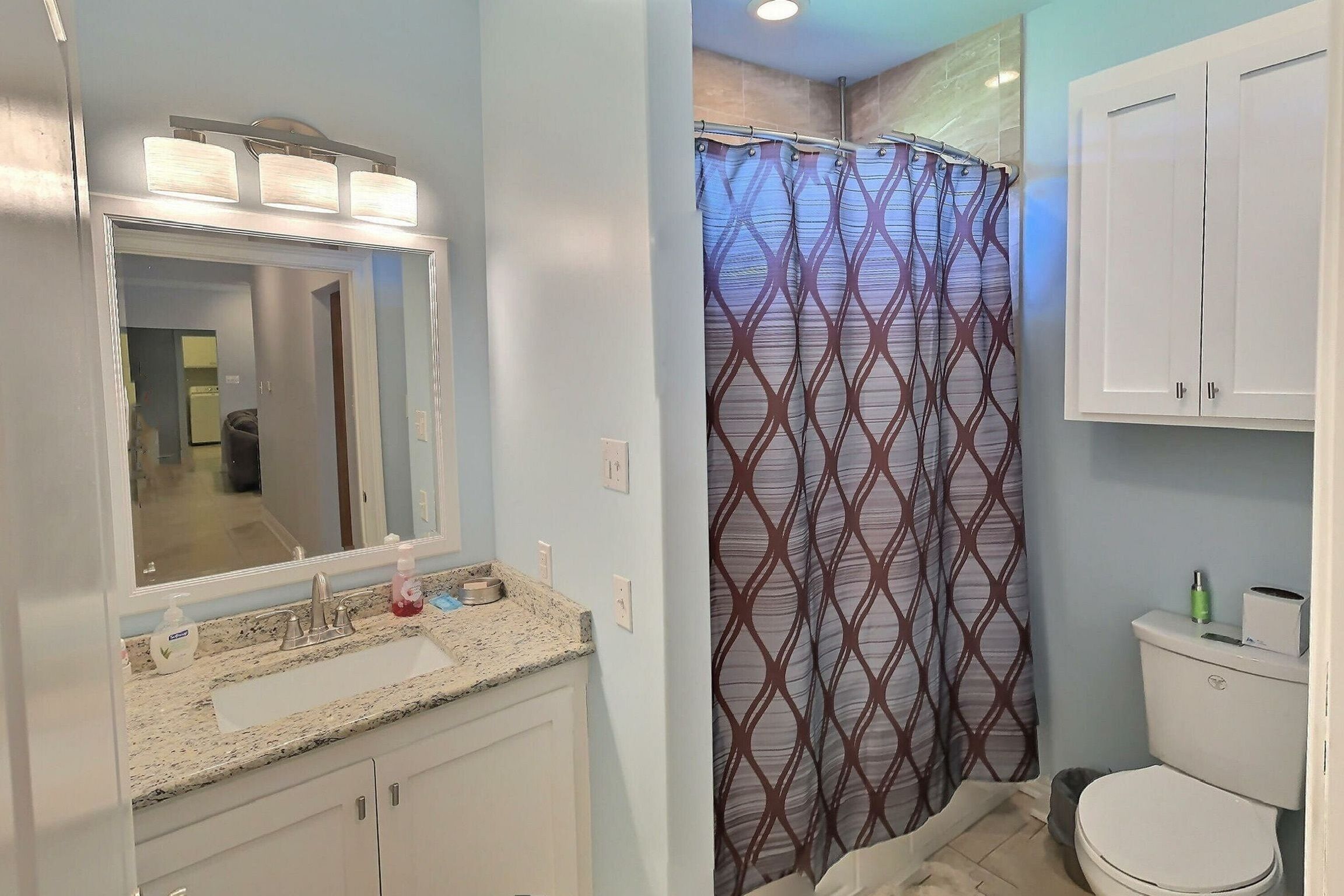 Une salle de bain avec un lavabo, un miroir et des toilettes.