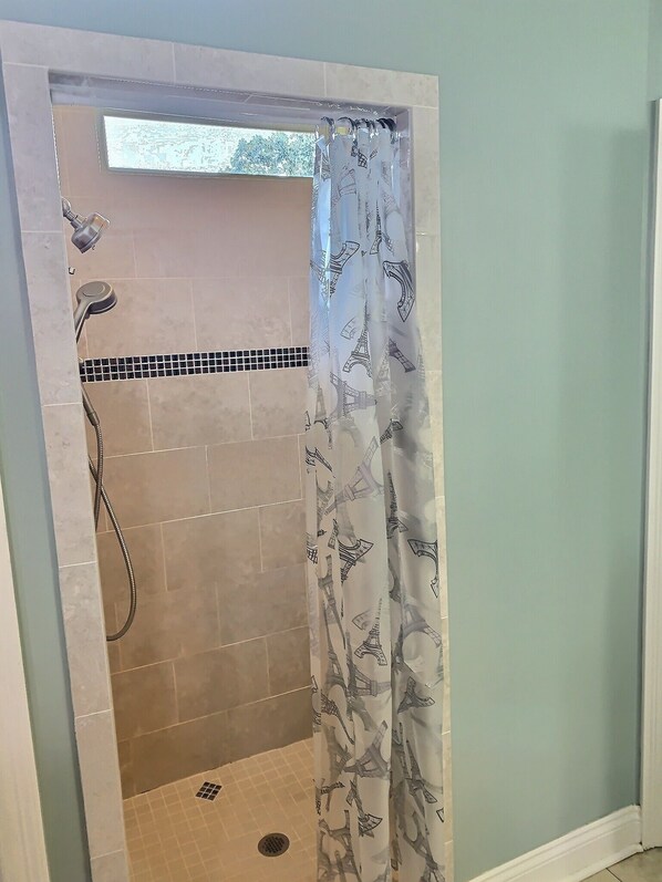 A shower with a curtain featuring a pattern of architectural structures.