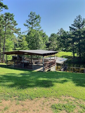 A covered outdoor area with a wooden deck, picnic tables, and a small bridge over a body of water. - How nice... Waterfront peace and quiet  *Wi-Fi!* (Many)
