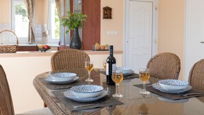 A dining area with a round table set for four, featuring blue and white patterned plates, wine glasses, and a bottle of wine.