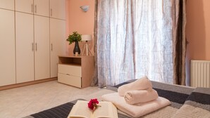 A bedroom with a bed, a bedside table with a lamp, a potted plant, and a window with curtains.