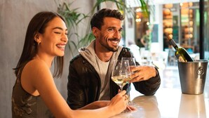 Un couple est assis à une table, avec une enseigne au néon en arrière-plan.