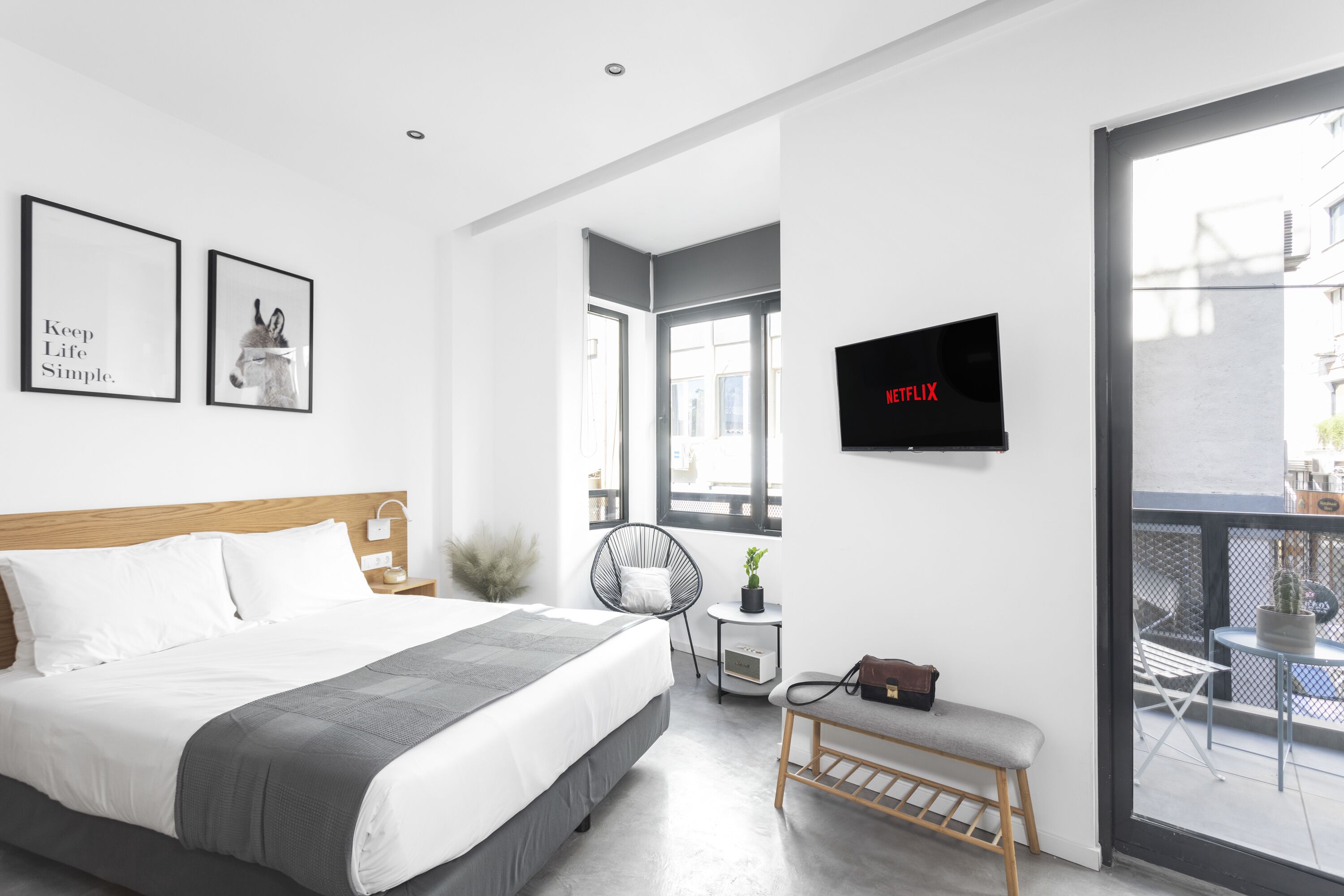 Une chambre d’hôtel moderne dotée d’un grand lit, d’une télévision, d’un balcon avec coin salon extérieur et offrant une vue sur la ville.