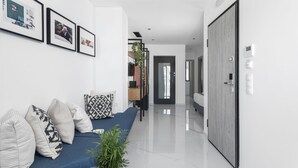 A modern living room with a blue sofa, patterned cushions, and a potted plant.