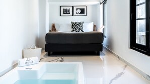 A modern bedroom with a large bed, a bathtub, and a view of the city.