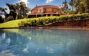 Une grande maison avec une piscine en premier plan.