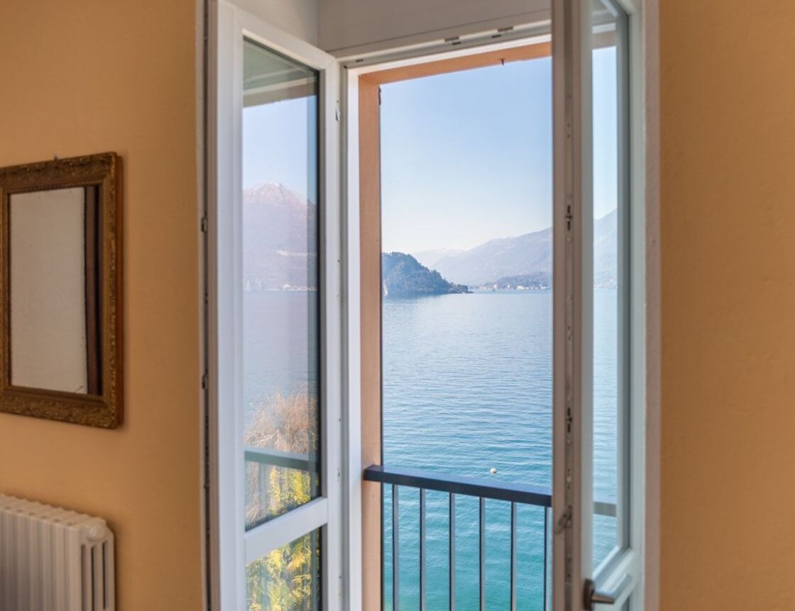 Een kamer met uitzicht op een meer en bergen, een radiator en een lijst met een afbeelding aan de muur.