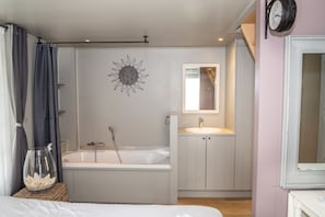 A modern bathroom with a freestanding bathtub, a vanity with a mirror, and a sun decoration on the wall. - Diane's Cottage (Knokke-Heist)