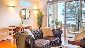 Una sala de estar moderna con un sofá de cuero, una mesa de comedor, sillas y un ventanal con vistas al exterior.