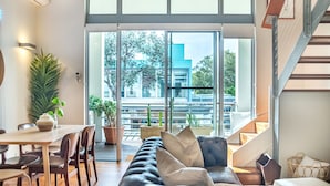 Una sala moderna con un sofá, una mesa de comedor y sillas. Se ve una escalera que sube a un nivel superior.