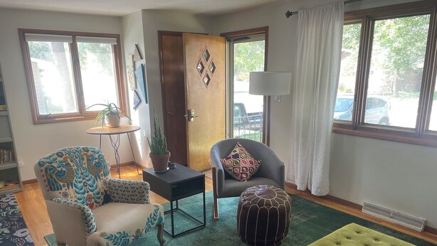 A living room with a sofa, armchair, ottoman, and a small table with a plant. - Comfortable and Quaint w/ a Hot Tub (Brookings)