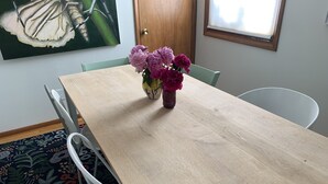 A dining table with a vase of flowers, surrounded by chairs, in a room with a door and a window. - Comfortable and Quaint w/ a Hot Tub (Brookings)