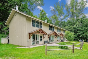 A two-story building with a sloped roof, large windows, and a covered porch area. - 2 bedroom Killington condo with fireplace, kitchen, and Wi-Fi. (Killington)