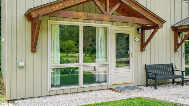 Un bâtiment doté d’un toit à pignon en bois, de grandes portes vitrées et d’un banc à l’extérieur.