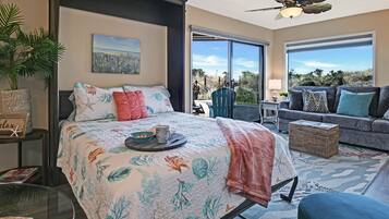 A bedroom with a bed, a nightstand, a potted plant, and a view of the outdoors.
