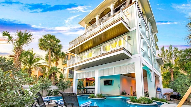 A multi-story hotel with a pool area, outdoor seating, and a covered patio. - Nearly Beachfront, One house from the beach! Pool and Game Room - Ocean Overlook (Siesta Key)