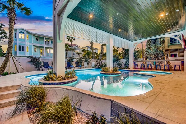 A pool area with multiple swimming pools, lounge chairs, and palm trees.