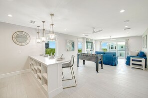 A spacious living area with a foosball table, a sofa set, and a dining table.