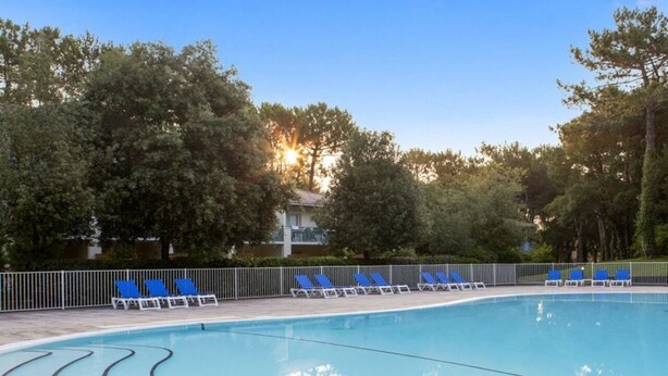 Una piscina con comode sedie a sdraio blu e una recinzione.