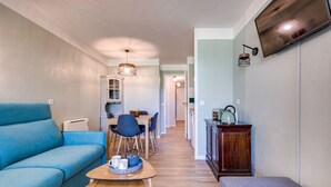 Un soggiorno moderno con un divano blu, un tavolino in legno e una zona pranzo con sedie e tavolo.