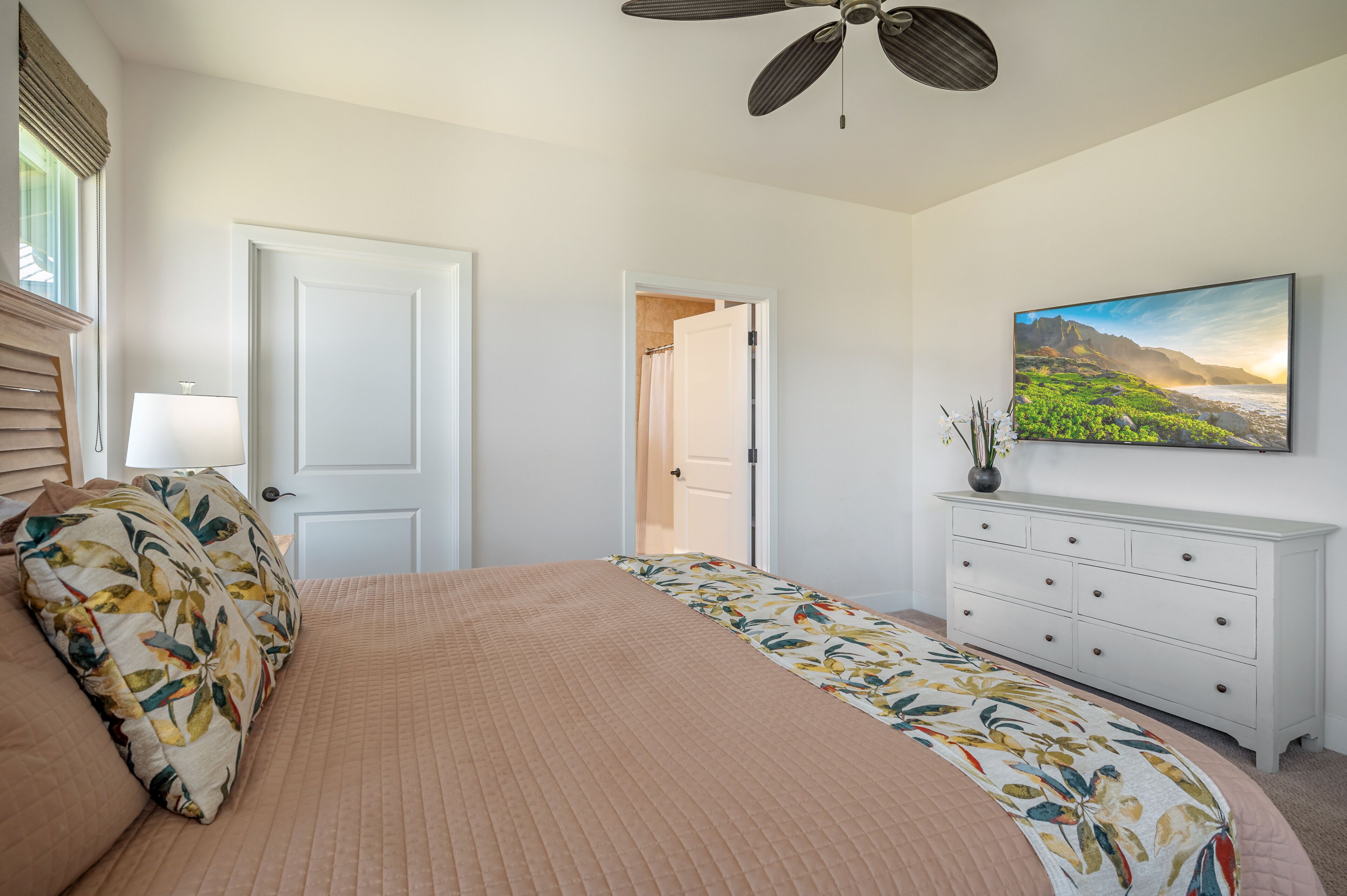 Un dormitorio con cama, cómoda, un cuadro y ventilador de techo.