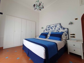 A bedroom with a bed, white wardrobe, and a nightstand with a lamp. - Scent of lemon (Minori)