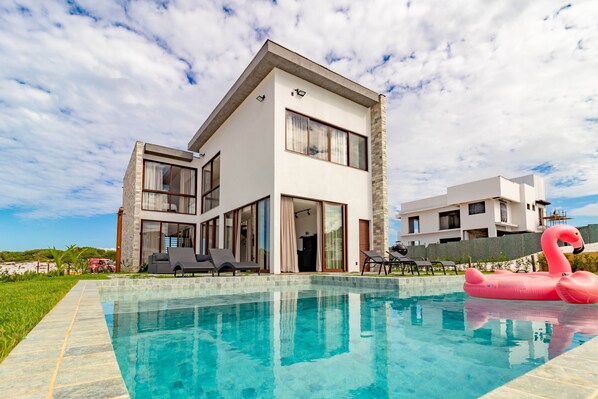 Una piscina al aire libre, sombrillas, sillones reclinables de piscina