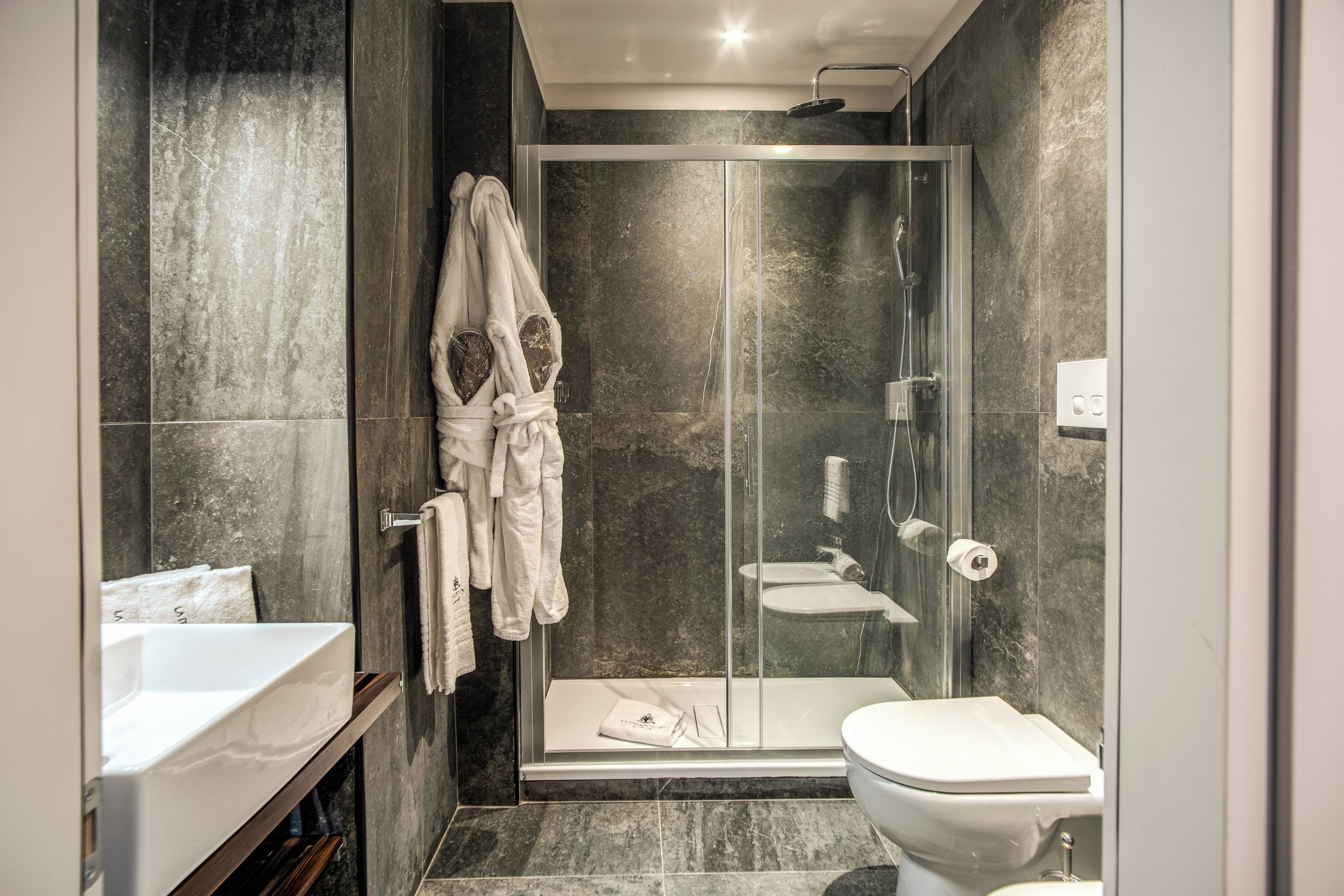 A modern bathroom with a glass-enclosed shower, a white sink, and a toilet.