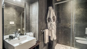 Un bagno moderno con uno specchio grande, un lavandino bianco e una cabina doccia in vetro.