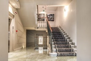 A modern interior with a marble staircase, a glass railing, and a framed picture on the wall. - Hotel 77 Seventy-Seven (Rome)