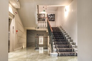 A modern interior with a marble staircase, a glass railing, and a framed picture on the wall.