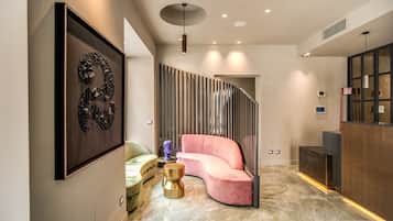 Een modern interieur met een gebogen roze bank, een ingelijste afbeelding, een bijzondere lamp en een receptiebalie.