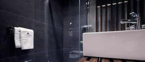 A modern bathroom with a bidet, a glass shower enclosure, and a wooden vanity.