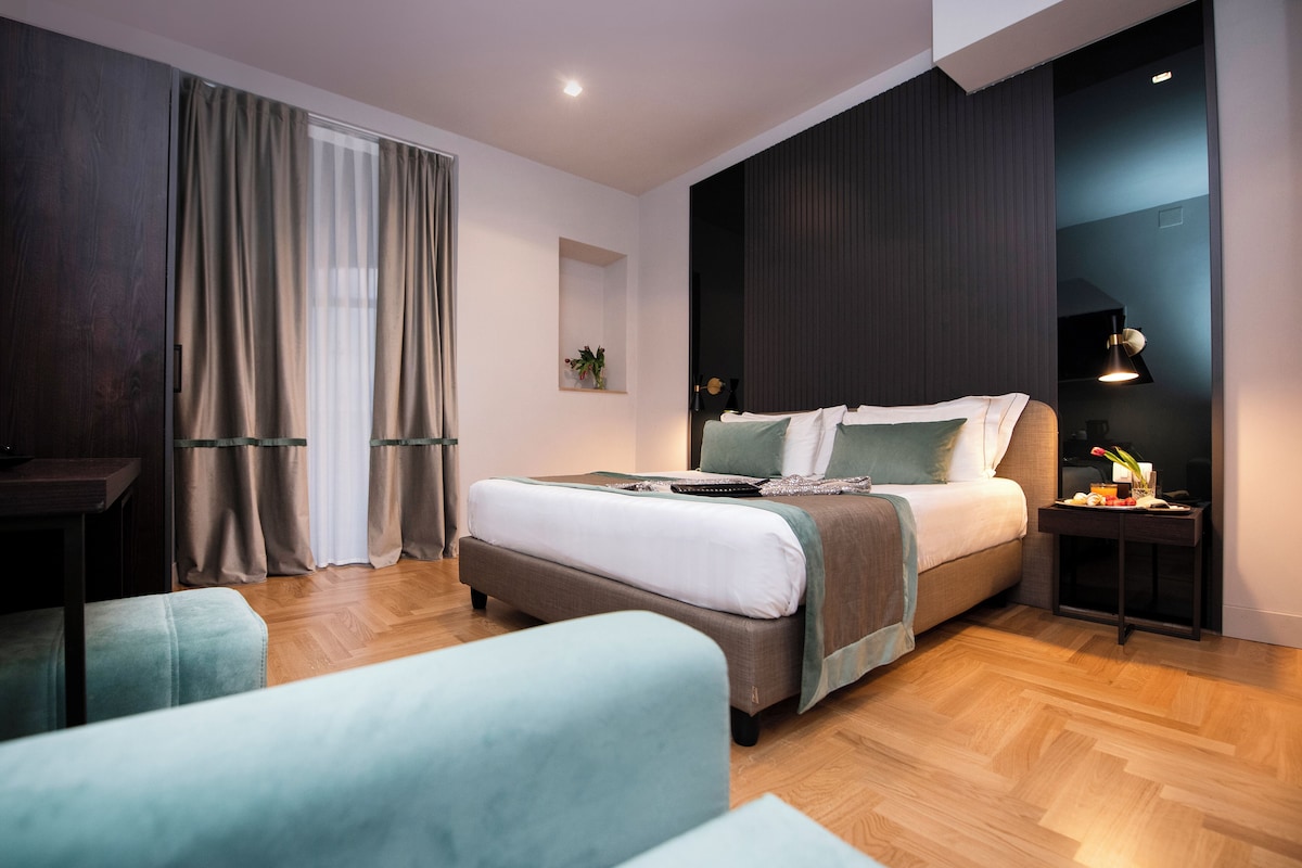 A modern bedroom with a large bed, a bedside table, a chair, and a desk.