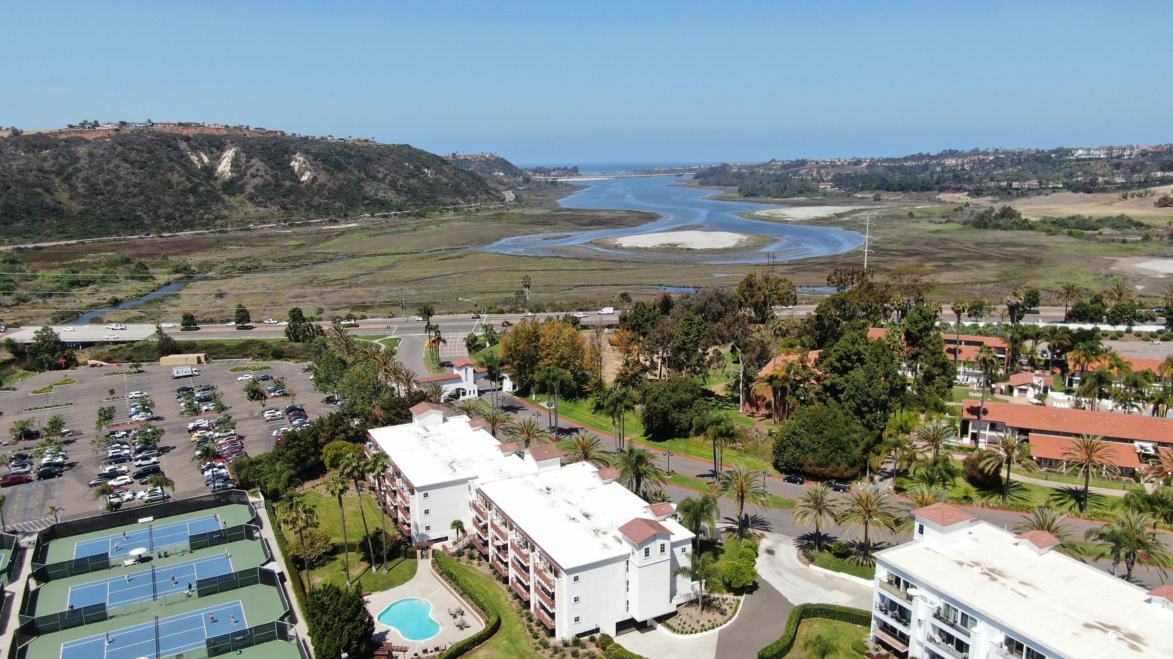 Un complexe hôtelier doté d’une piscine, de courts de tennis et offrant une vue sur une rivière et une plage.