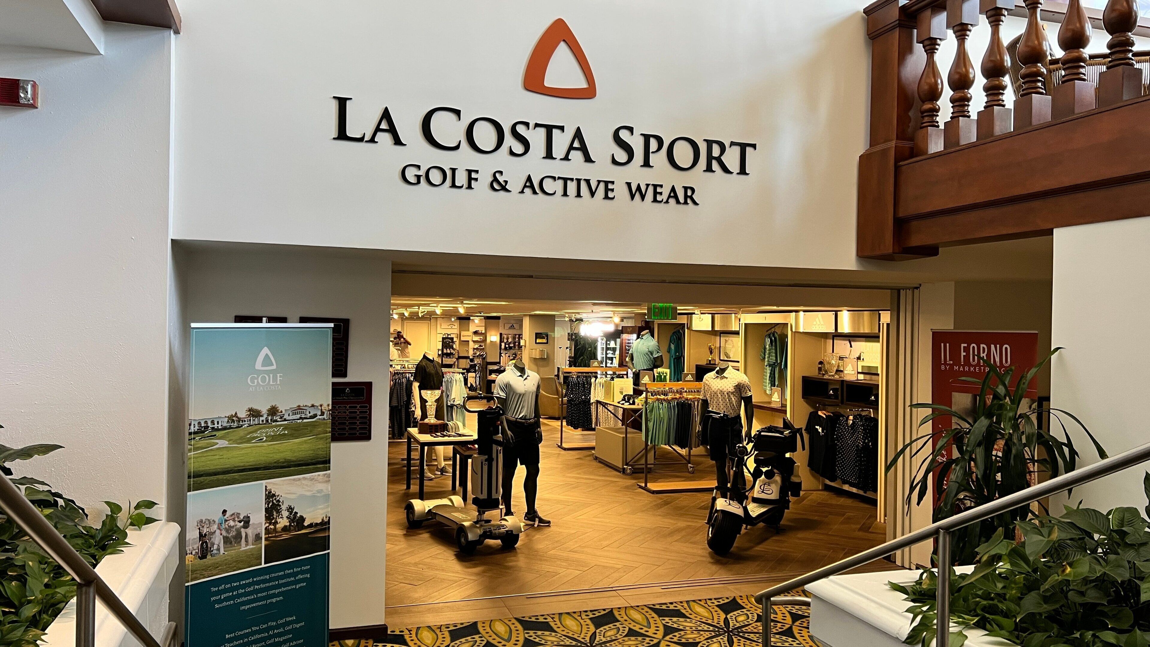 The entrance to La Costa Sport, a golf and active wear store with a wooden staircase and indoor plants.