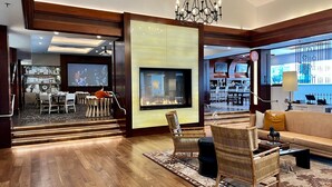 A spacious living area with a fireplace, comfortable seating, and a bar area visible through an open door. - Private Balcony Overlooking Pool | Gated Parking (Carlsbad)