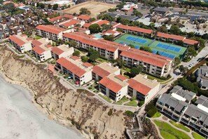A coastal residential area with apartment buildings, a tennis court, and a beach. - Oceanfront Views, Heated Pool, Hot Tubs, BBQ (Solana Beach)