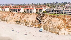 Et kysthotel med flere bygninger, en sandstrand og en klippekant.