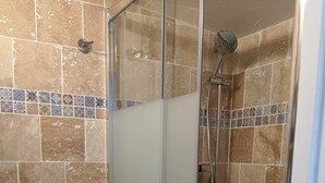 Ein Badezimmer mit Duschkabine, Toilette und Fliesenwänden.