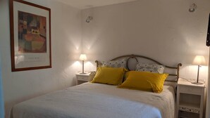 Ein Schlafzimmer mit einem Bett, zwei Nachttischen, einem Beistelltisch, einem gerahmten Bild und einer Lampe auf jeder Bettseite.
