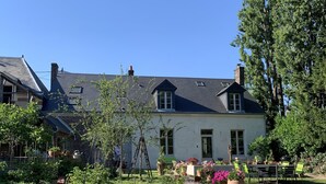 Ein zweistöckiges Haus mit Garten, Terrasse und Essbereich.
